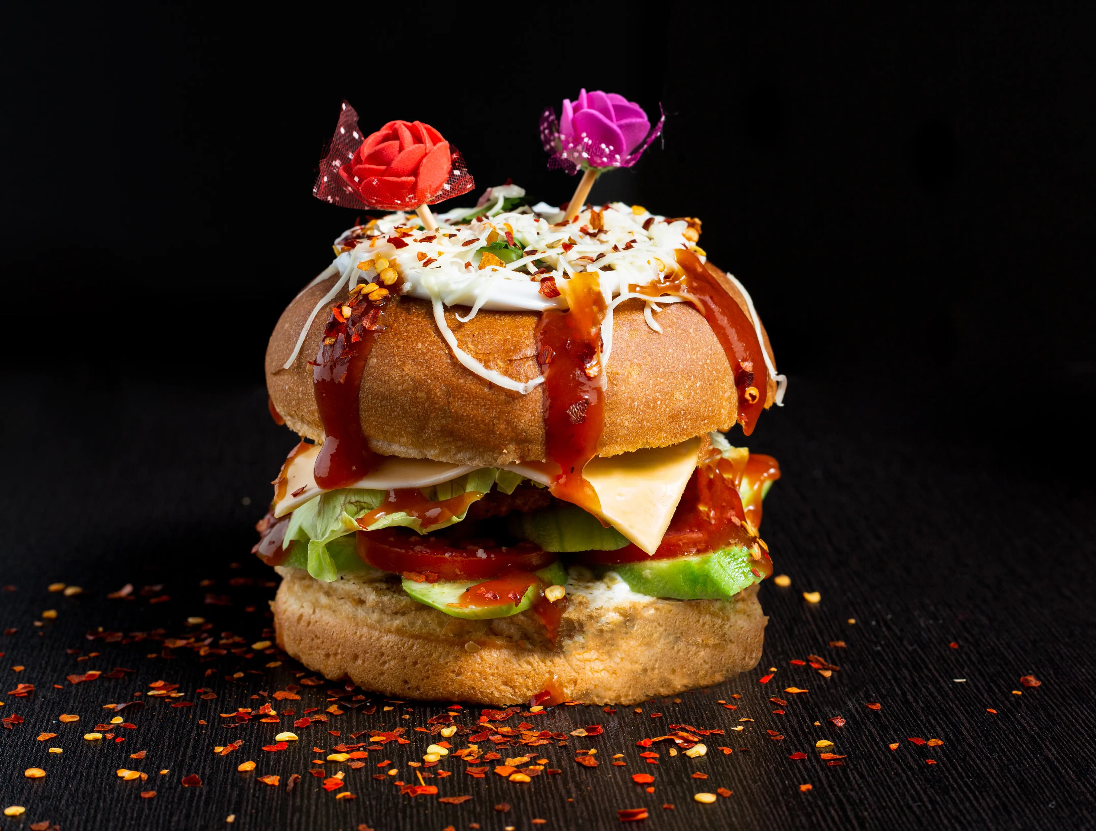 Loaded burger with melting cheese and sauces on a dark backdrop — food photography Udaipur